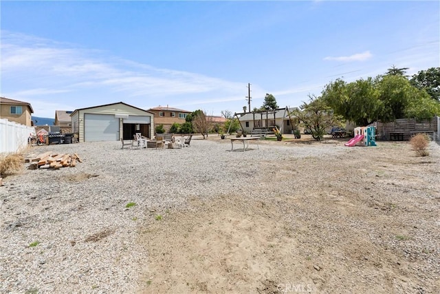 681 E Washington Ave, San Jacinto, CA 92583 - view of yard featuring a detached garage, fence, an outbuilding, and a playground