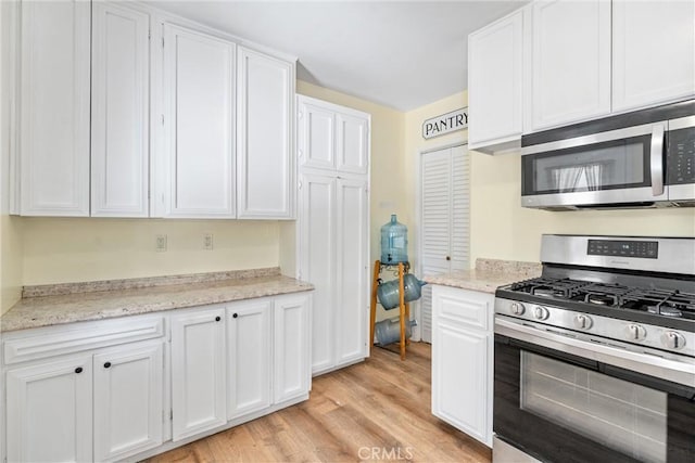 681 E Washington Ave, San Jacinto, CA 92583 - kitchen with stainless steel appliances, white cabinets, light wood-style flooring, and light stone counters