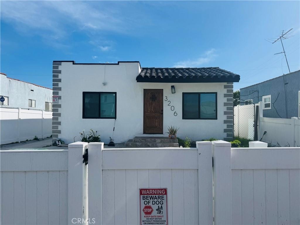 view of front of home featuring stucco siding, a gate, and a fenced front yard