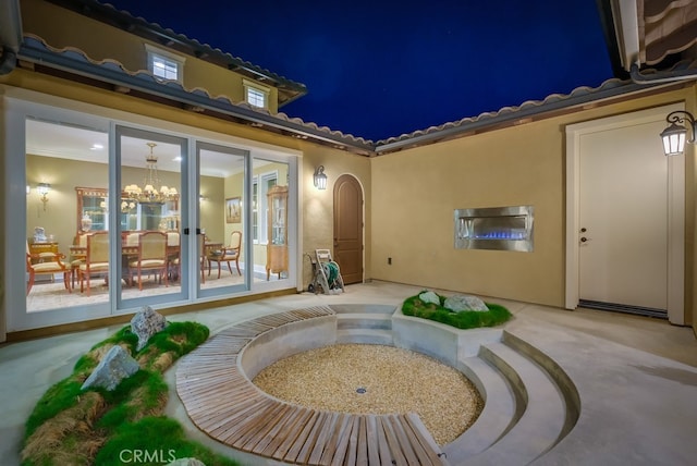 exterior entry at twilight featuring a tile roof and stucco siding