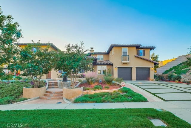 view of front of house with an attached garage, a tile roof, stucco siding, and concrete driveway