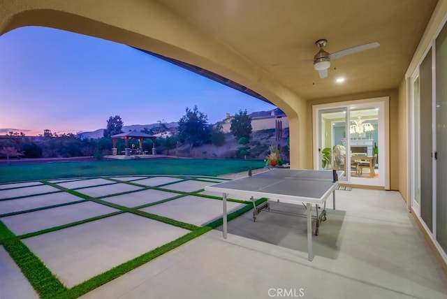 patio terrace at dusk featuring a gazebo and ceiling fan