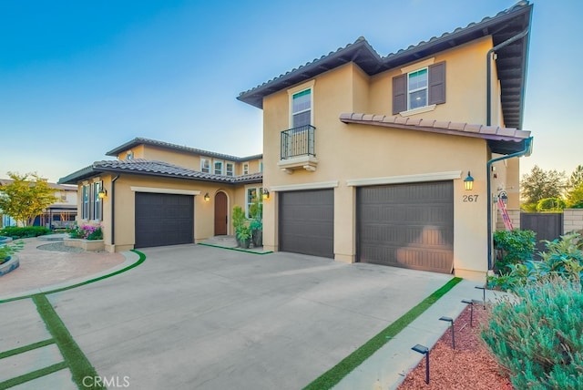 view of front of property with a balcony, concrete driveway, an attached garage, a tile roof, and stucco siding
