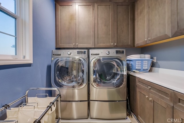 laundry area featuring cabinet space, a textured wall, and washing machine and clothes dryer
