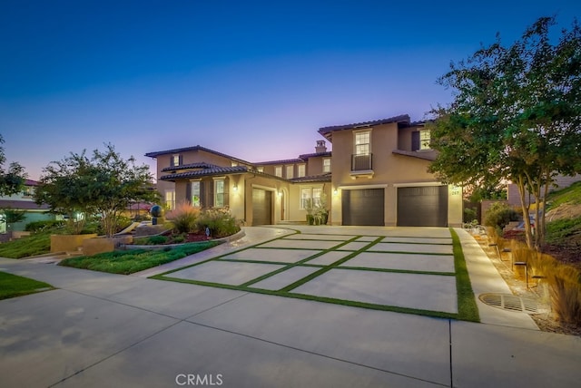 view of front of property featuring a garage, a tile roof, driveway, and stucco siding