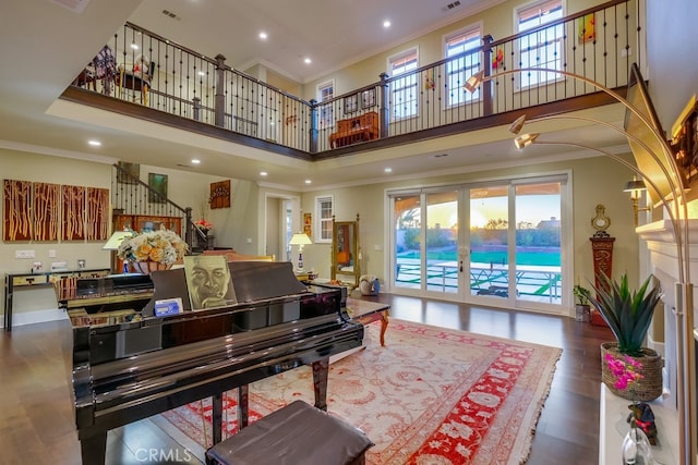 living room with plenty of natural light, a towering ceiling, stairway, and crown molding