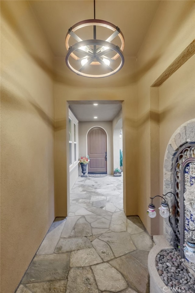 corridor featuring arched walkways, stone tile floors, and a high ceiling