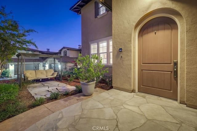 view of exterior entry featuring a patio area and stucco siding