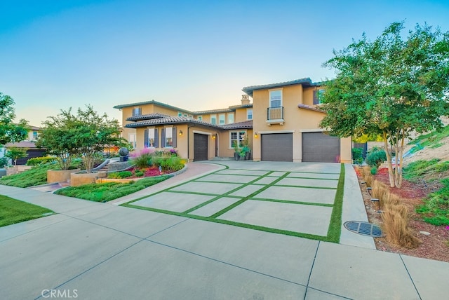 view of front of home featuring an attached garage, a tile roof, stucco siding, and concrete driveway