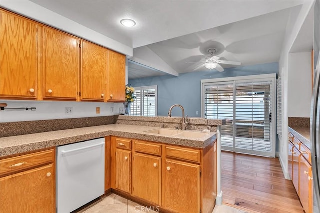 kitchen featuring vaulted ceiling, a sink, dishwasher, ceiling fan, and a peninsula