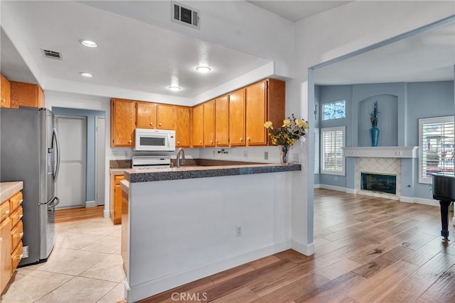 kitchen featuring visible vents, range, freestanding refrigerator, and white microwave
