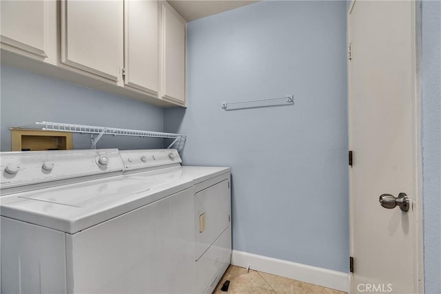 laundry area featuring baseboards, independent washer and dryer, light tile patterned floors, and cabinet space
