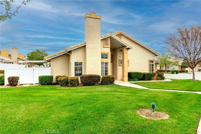 mid-century modern home with a front yard, a chimney, a tiled roof, and fence