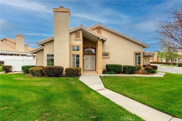 view of front of home with a chimney, fence, stucco siding, a tile roof, and a front yard