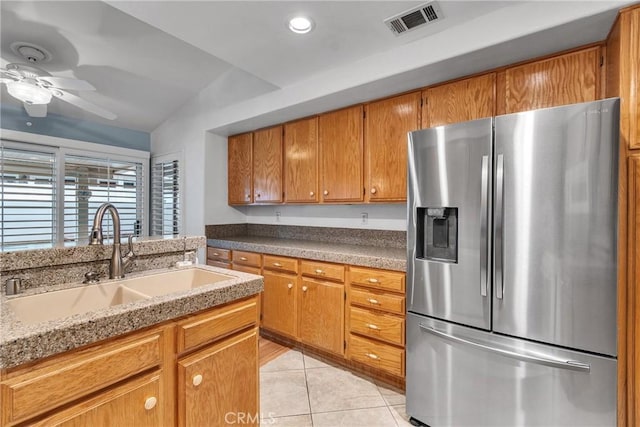 kitchen with brown cabinets, visible vents, light tile patterned floors, a sink, and stainless steel refrigerator with ice dispenser