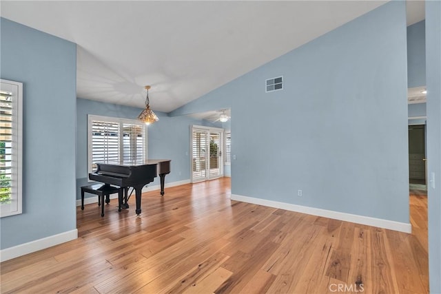 dining space featuring high vaulted ceiling, light wood-style flooring, visible vents, and baseboards