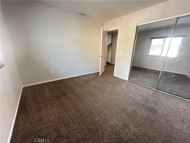 unfurnished bedroom with carpet flooring, visible vents, a closet, and baseboards