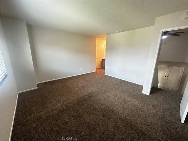 unfurnished bedroom featuring dark carpet, baseboards, and visible vents