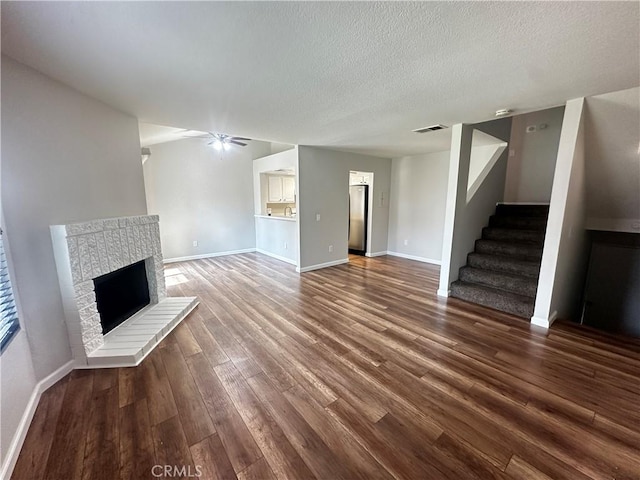 unfurnished living room featuring visible vents, baseboards, dark wood-style flooring, a ceiling fan, and stairs