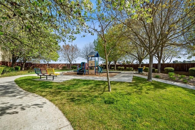community jungle gym featuring a lawn and fence