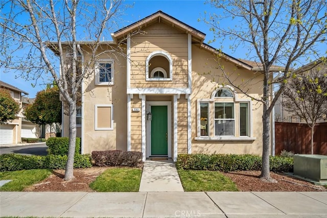 view of front facade featuring stucco siding and fence