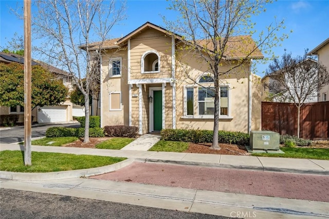 view of front of home with stucco siding, fence, and a garage