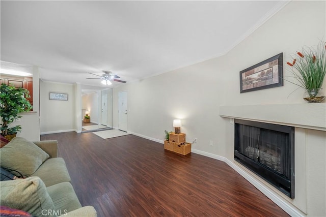 living area featuring crown molding, a fireplace, wood finished floors, baseboards, and ceiling fan