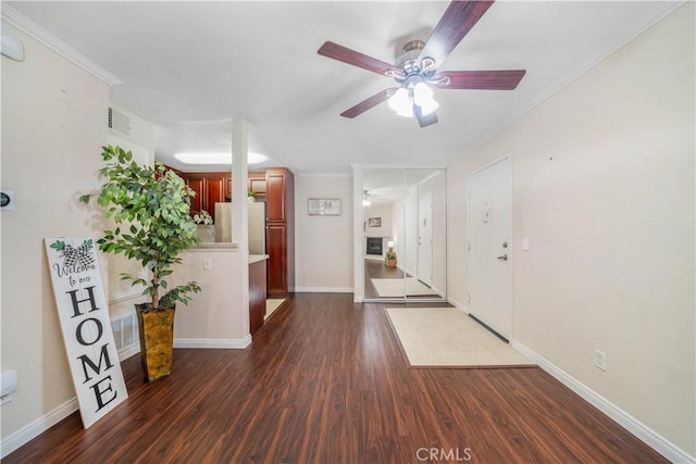 foyer entrance featuring visible vents, baseboards, ceiling fan, ornamental molding, and dark wood finished floors