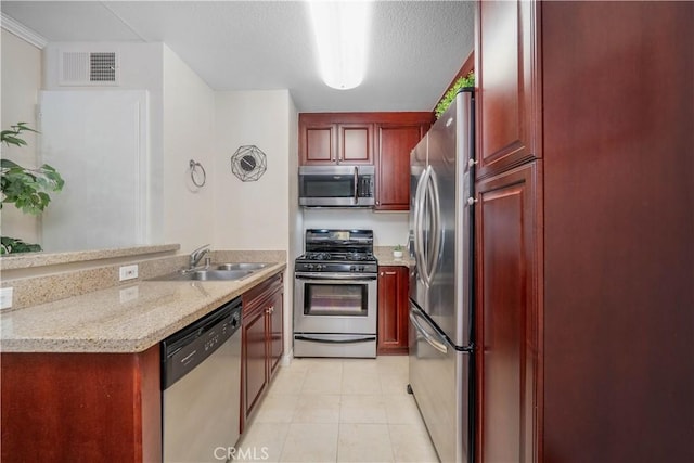 kitchen featuring a sink, visible vents, a peninsula, dark brown cabinets, and appliances with stainless steel finishes