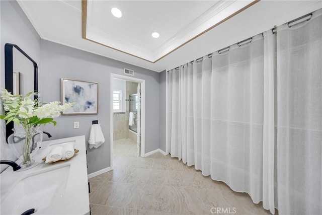 full bathroom featuring visible vents, ornamental molding, a sink, and a raised ceiling