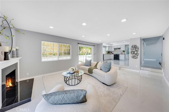 living room with baseboards, a lit fireplace, and recessed lighting