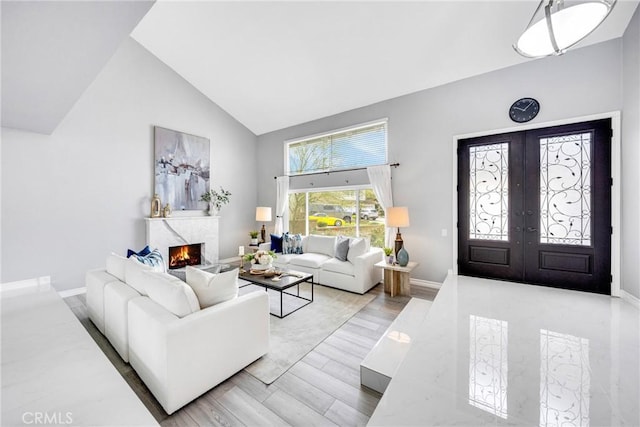 living area featuring baseboards, a fireplace, high vaulted ceiling, and french doors