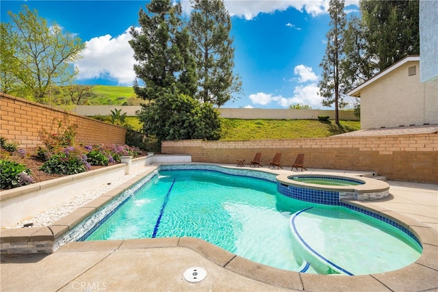 view of swimming pool with a fenced backyard, a pool with connected hot tub, and a patio area