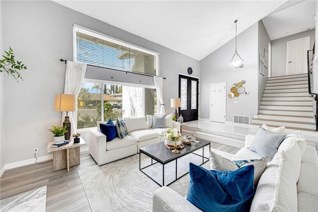 living room featuring stairs, high vaulted ceiling, wood finished floors, baseboards, and visible vents