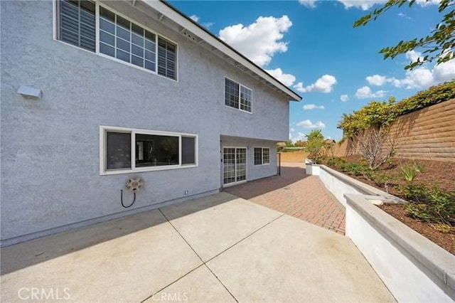 rear view of house with stucco siding, fence private yard, and a patio area