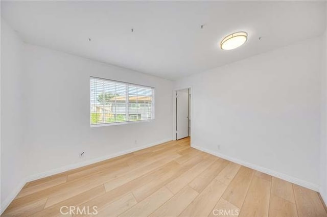 unfurnished room with baseboards and light wood-type flooring