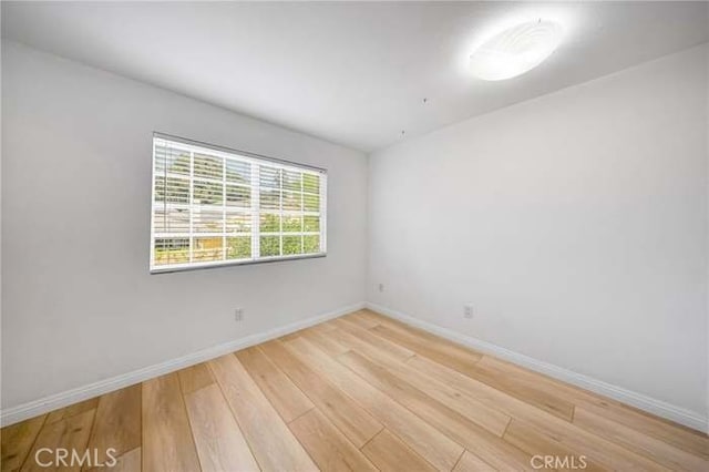 empty room featuring baseboards and light wood finished floors
