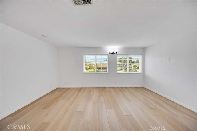 unfurnished room with baseboards, light wood-style floors, and visible vents