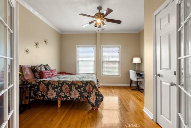 bedroom with baseboards, a ceiling fan, wood finished floors, and crown molding