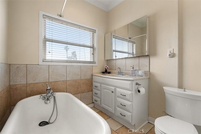 bathroom featuring ornamental molding, toilet, a freestanding tub, tile patterned floors, and vanity