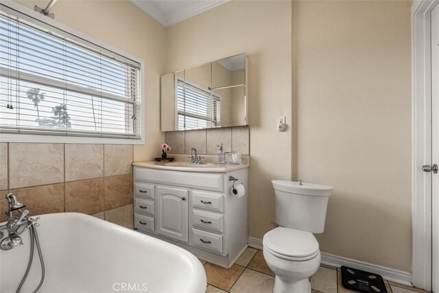 full bathroom with tile patterned floors, crown molding, toilet, vanity, and a soaking tub