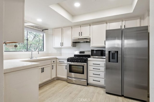 2903 Yucatan Pl Unit A, Diamond Bar, CA 91765 - kitchen with tile countertops, appliances with stainless steel finishes, under cabinet range hood, a raised ceiling, and light wood finished floors