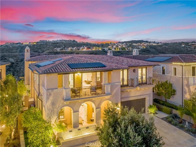 31 Seawatch, Newport Coast, CA 92657 - back of property featuring a balcony, solar panels, a garage, a chimney, and stucco siding
