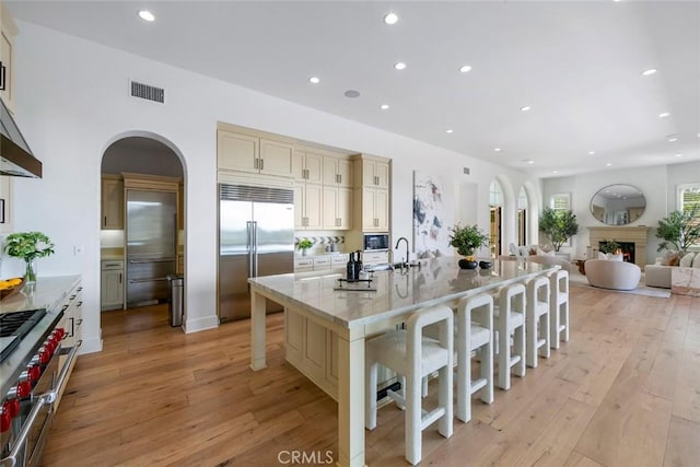 31 Seawatch, Newport Coast, CA 92657 - kitchen featuring built in appliances, a breakfast bar, light wood finished floors, recessed lighting, and cream cabinets