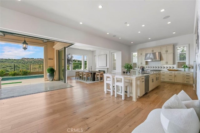 31 Seawatch, Newport Coast, CA 92657 - kitchen featuring cream cabinetry, under cabinet range hood, open floor plan, stainless steel dishwasher, and light wood-style flooring