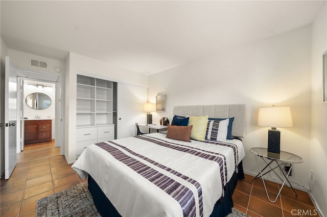 tiled bedroom with a sink, a closet, baseboards, and visible vents