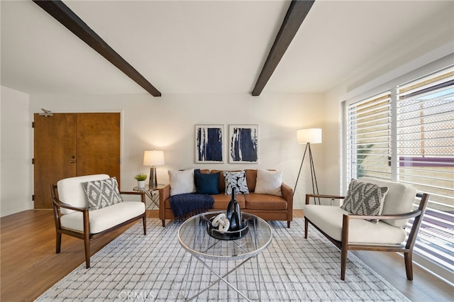 living area with wood finished floors and beam ceiling