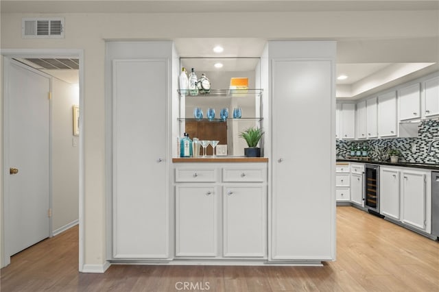 bar featuring wine cooler, backsplash, bar area, visible vents, and light wood-style floors