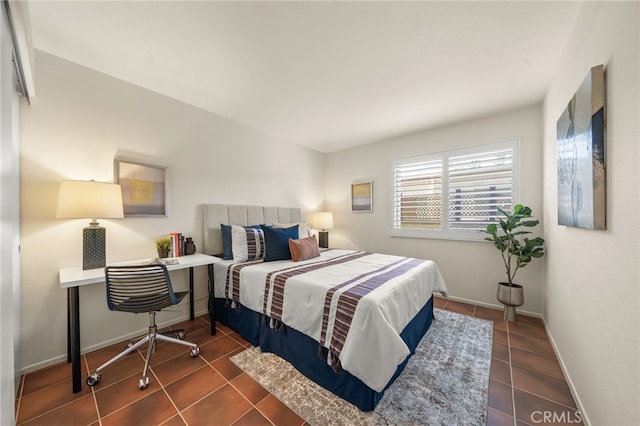 bedroom featuring baseboards and dark tile patterned flooring