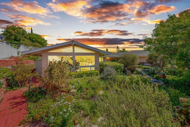 back of property at dusk featuring stucco siding and fence